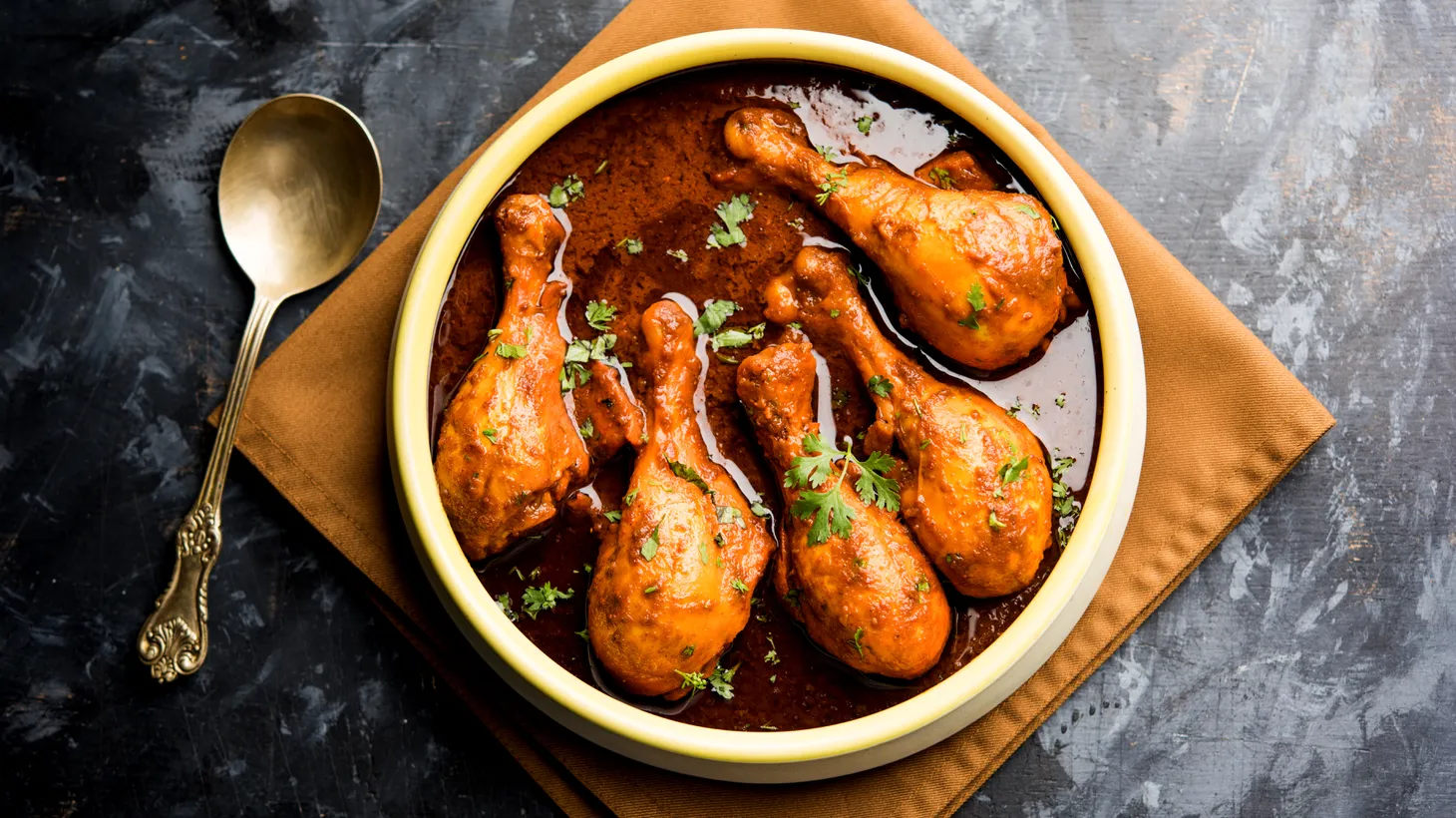 Chicken drumsticks prepared as Murg Tangdi are served in a bowl of fragrant sauce.