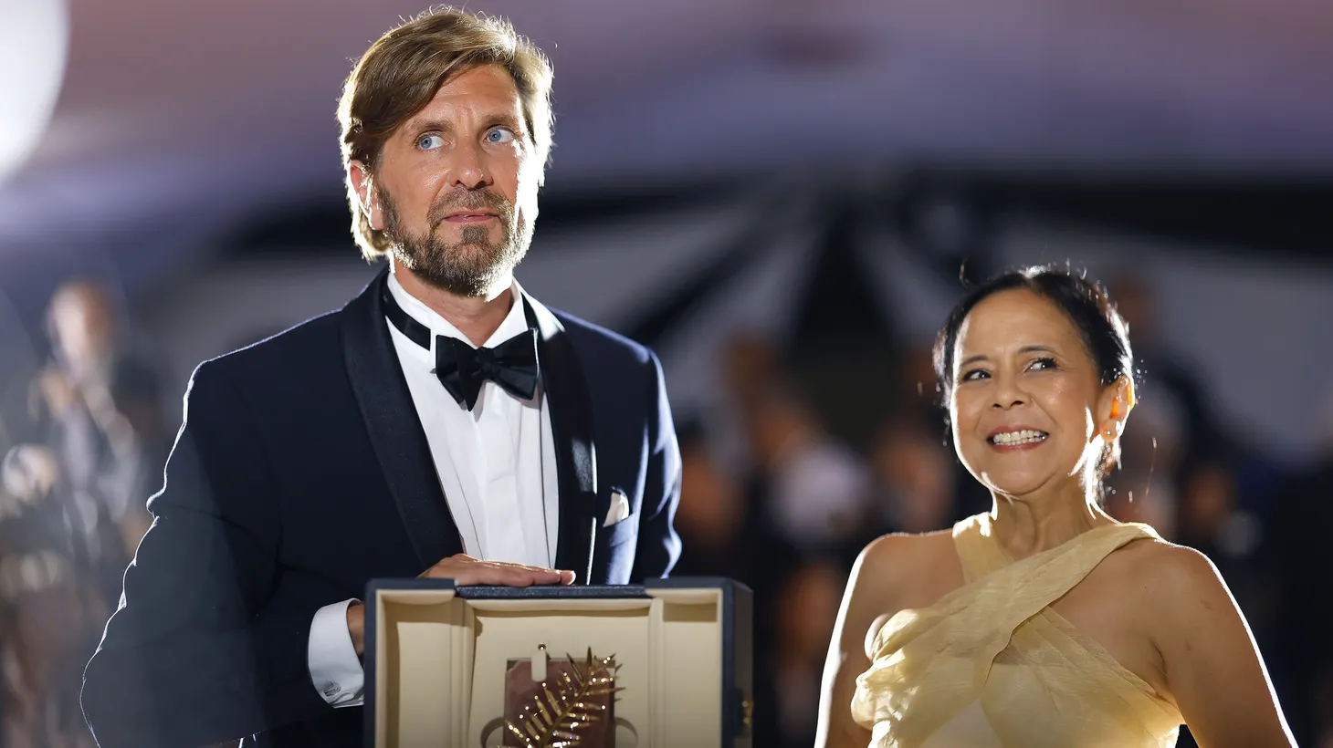 Director Ruben Östlund and actress Dolly De Leon pose with a Palme d'Or award for the film “Triangle of Sadness” at the 75th Cannes Film Festival’s closing ceremony on May 28, 2022.
