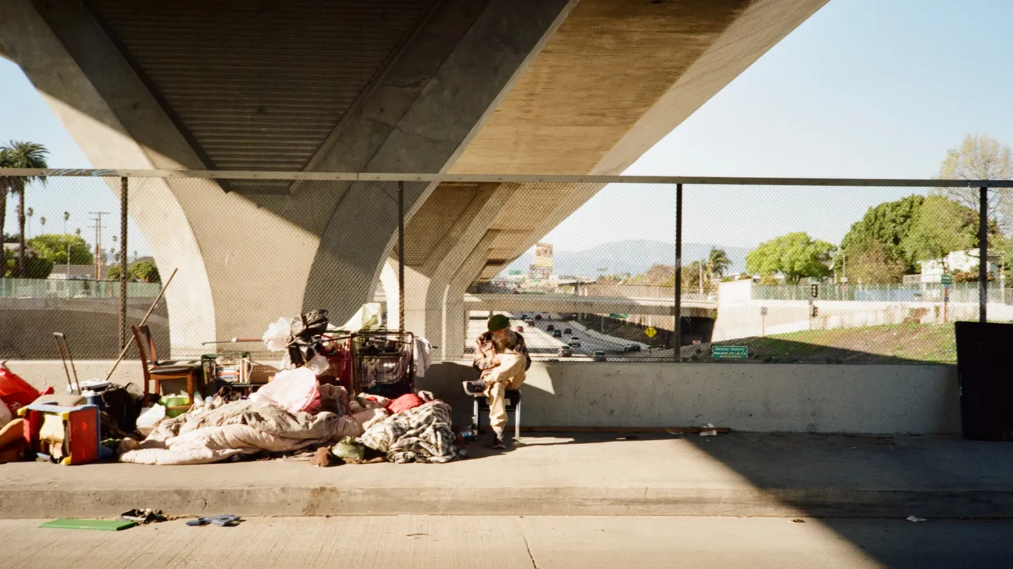 An unhoused person sits under the 110 freeway overpass in Vernon, California, March 2023.