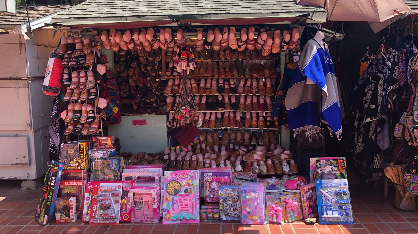 Business is slow at this Olvera Street puesto, which is selling huarches alongside cheap trinkets and toys. Another stall (left) has already closed for the day. “The crowds just aren’t coming back,” says Olvera Street merchant Valerie Hanley.