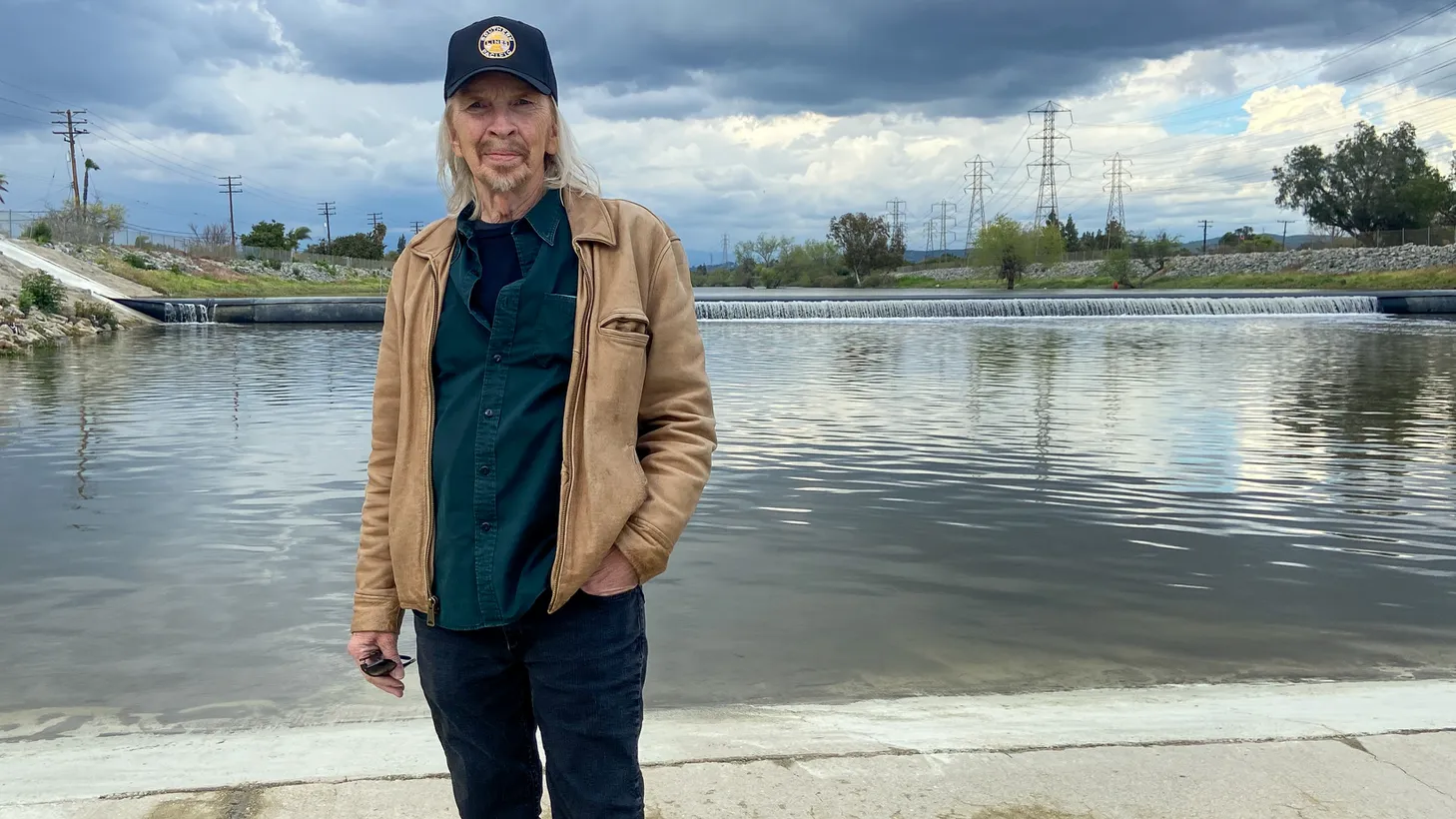 Dave Alvin stands by the San Gabriel river, where he frequently played as a kid, catching jackrabbits and rattlesnakes on its then unpaved shores.
