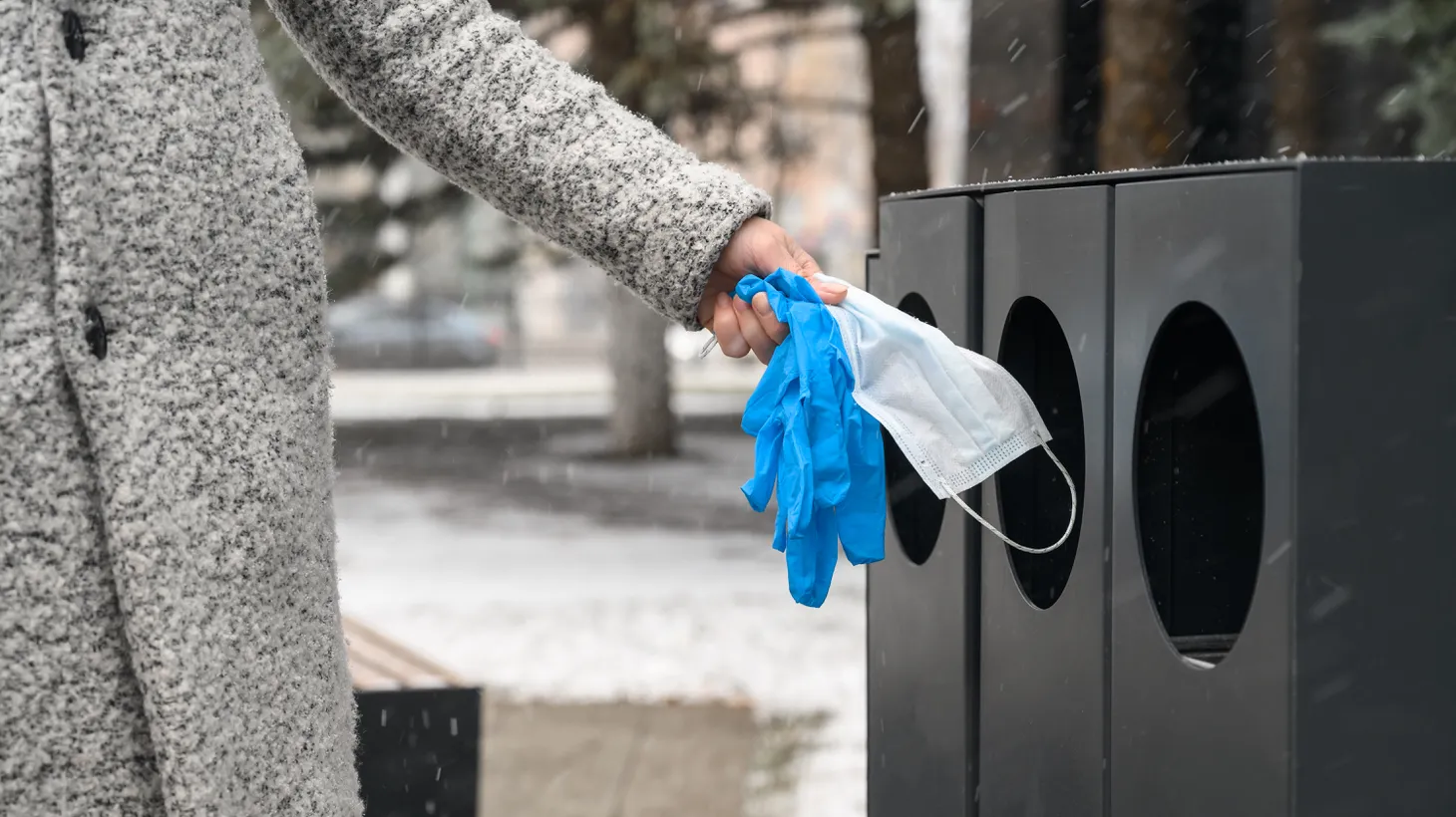 A person throws a mask and gloves into a trash bin. Highlighting racial disparities reduces fear of COVID among white people, and lowers support for masks and other safety measures, according to a new study published in ScienceDirect.
