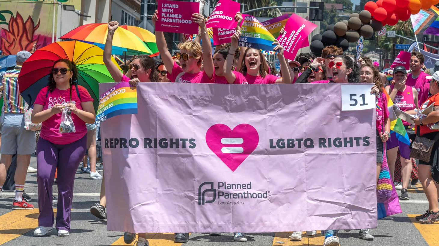 Activists walk with a Planned Parenthood LA banner that says, “Repro rights = LGBTQ rights.”