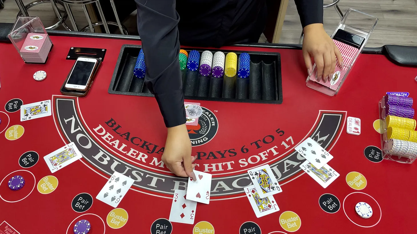 Michelle Fernandez, an instructor at the Millennium Casino Academy, demonstrates how table games are played in California’s card rooms. If Proposition 26 passes, they could be forced to change the way they do business or shut down.