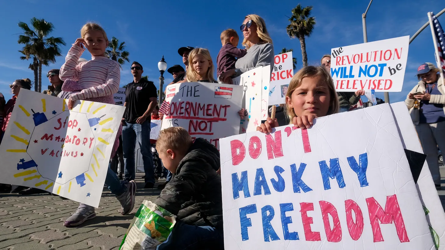 Protestors hold signs that say “don’t mask my freedom” and “stop mandatory vaccines” in Huntington Beach, Jan. 3, 2022.