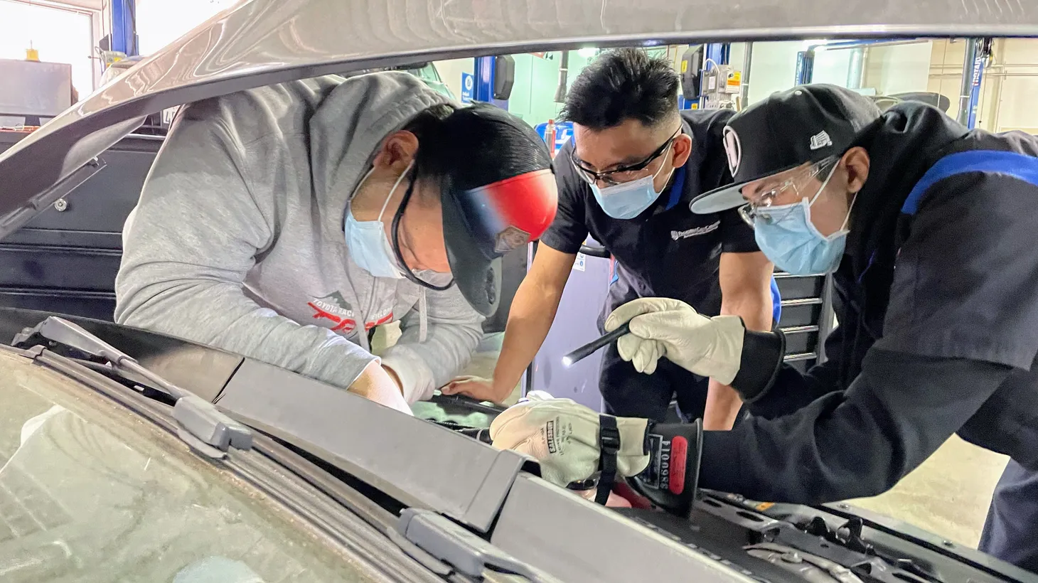 (L to R) Pasadena City College automotive technician students Tahar Ellouz, Javier Compos and Joshua Wharton, work to access the battery of an all-electric Chevy Bolt during the lab of an introductory course on electric car repair.