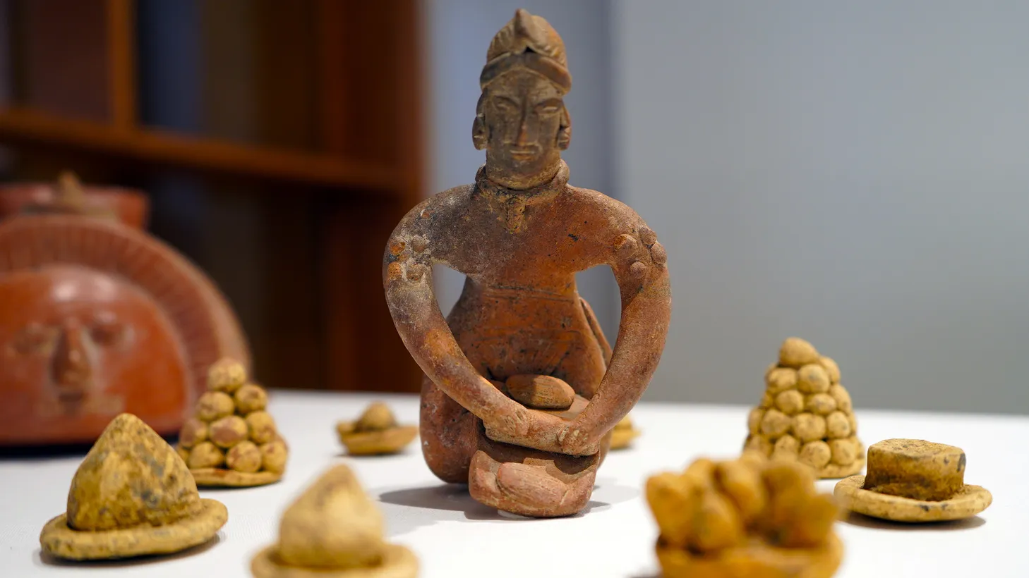 An artifact from Oaxaca, Mexico on display at LA Cocina features a kneeling figure making masa with mano and metate, a stone grinding tool.