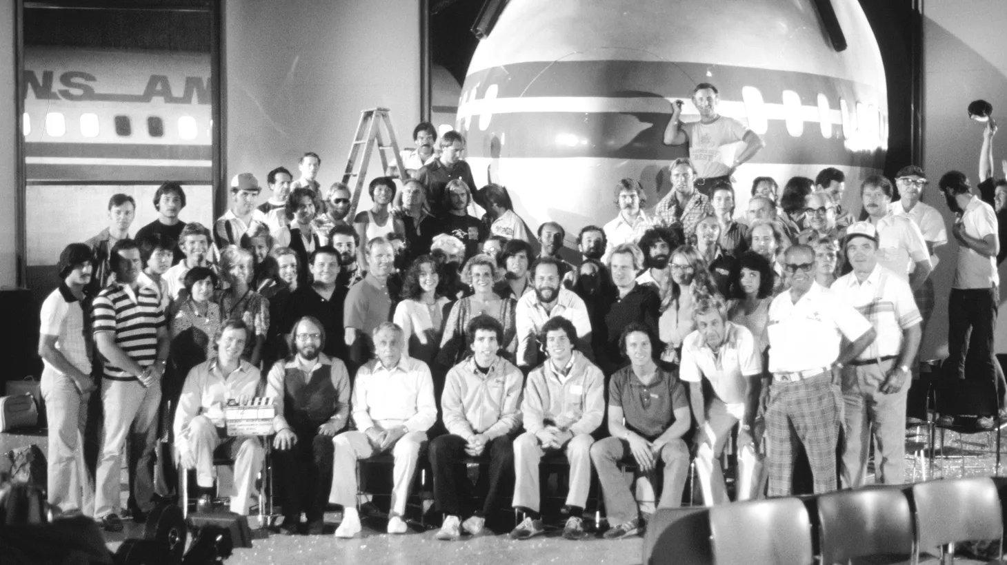 The cast and crew of “Airplane!” pose for a group photo after filming the final scene of the 747 crashing through the terminal.