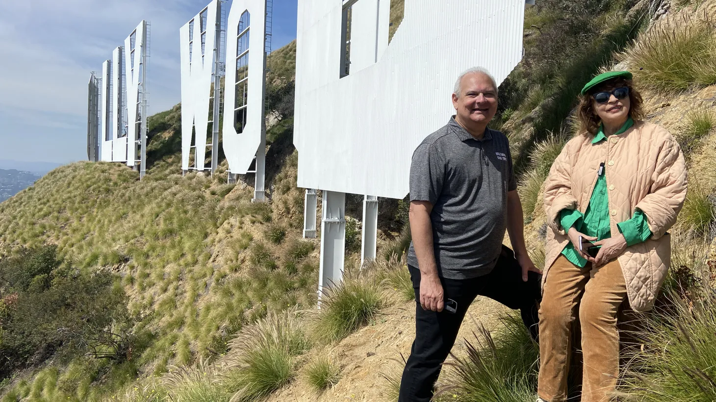 Hollywood Sign Trust Chairman Jeff Zarrinnam and LA Times Columnist Patt Morrison stand next to the sign on Mount Lee.
