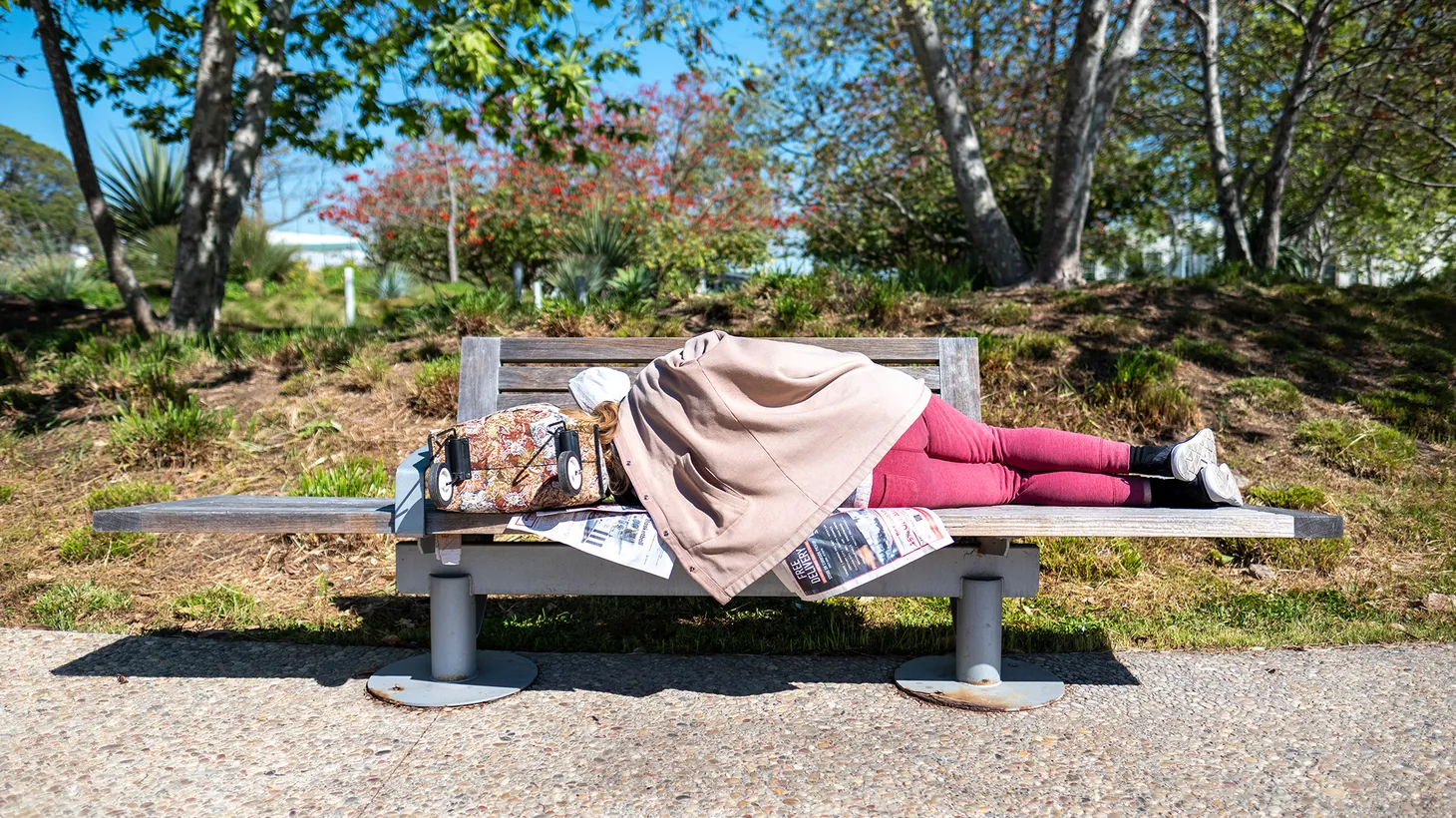 An unhoused person sleeps on a bench in Tongva Park, Santa Monica, CA, February 25, 2022.