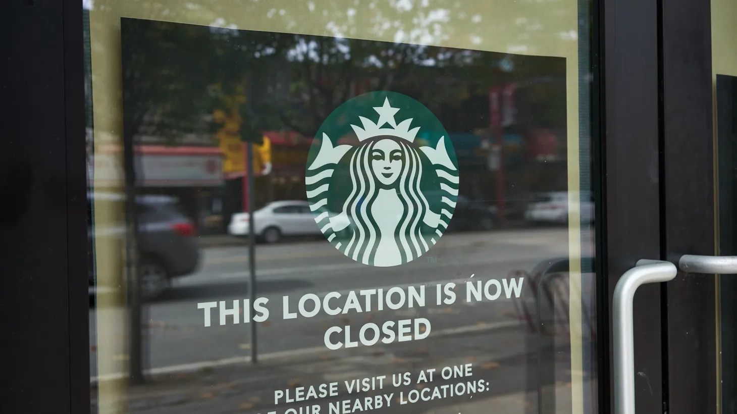 “This location is now closed,” a sign says on the door of a Starbucks.