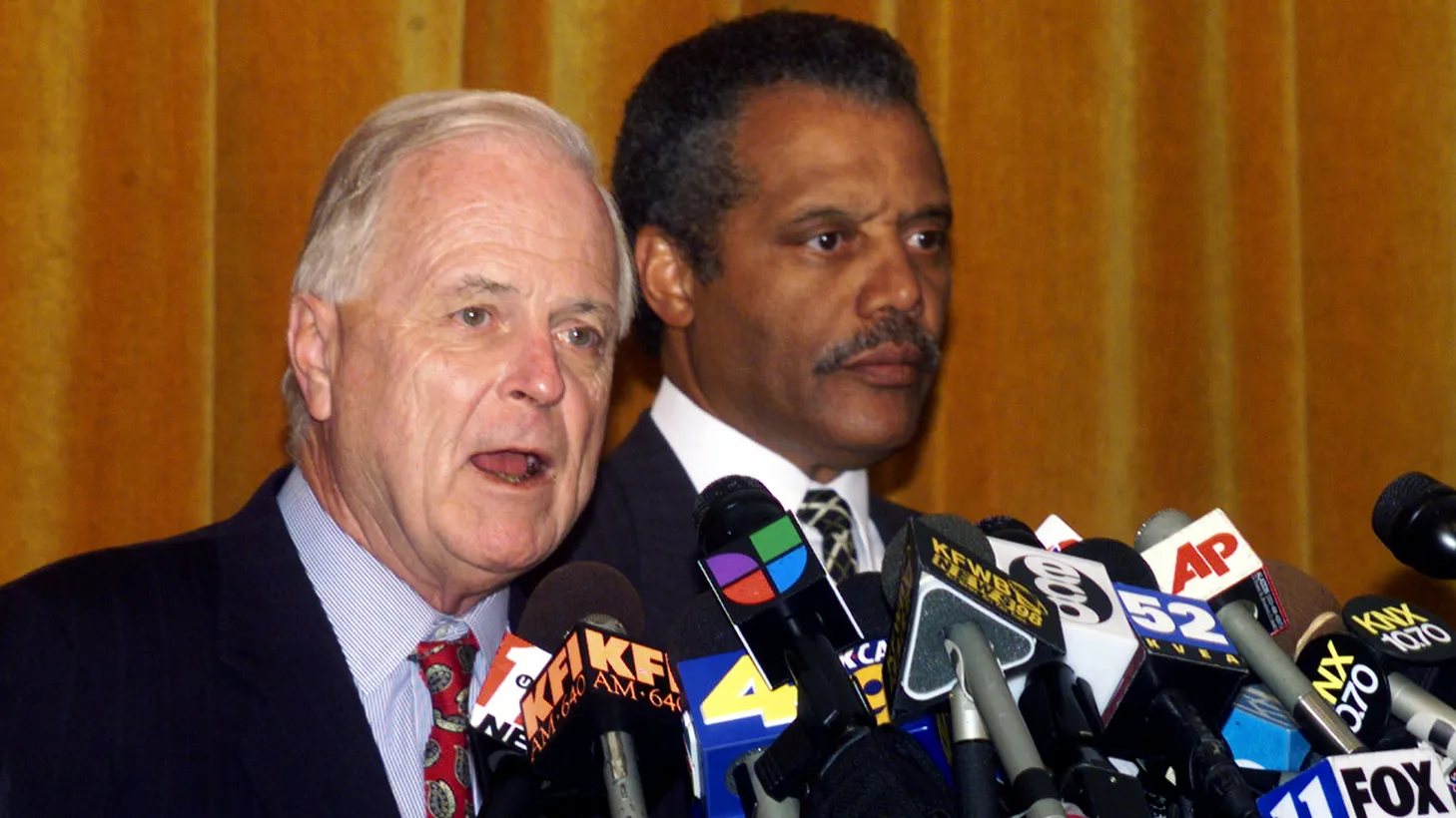 Los Angeles Mayor Richard Riordan (L) speaks to reporters with Los Angeles Police Chief Bernard Parks (R) during a news conference at police headquarters in Los Angeles, August 1999.