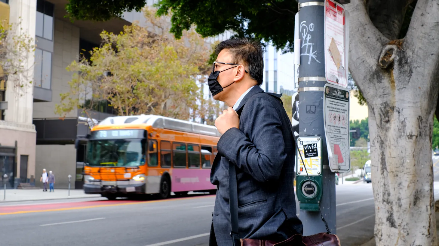 A man wears a mask at an intersection in downtown LA.