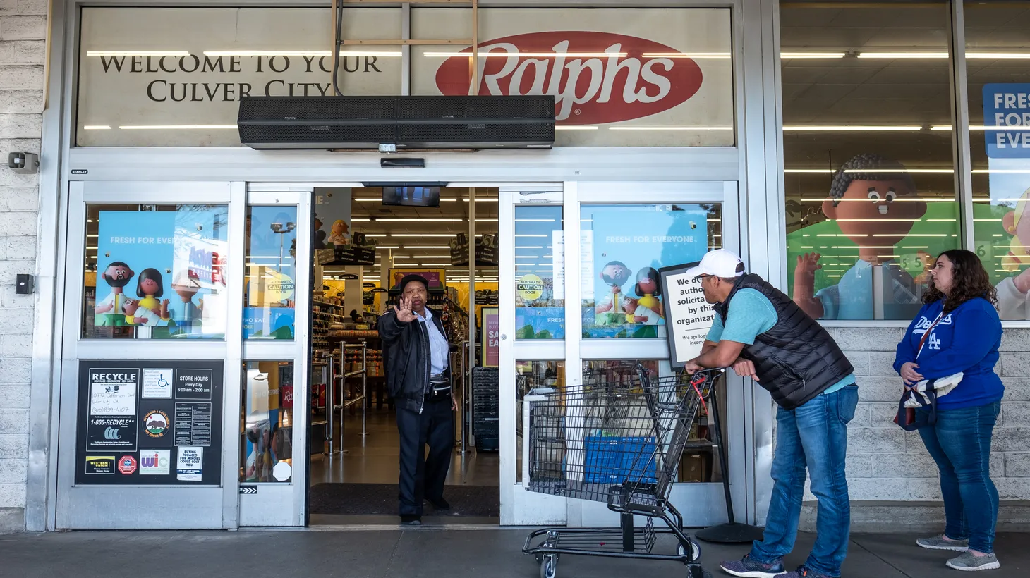 A security officer guards the entrance of Ralphs in Culver City, CA, as shoppers stand outside. Mike Iovino, who works at a Ralphs in Studio City, says grocery store employees deserve to be better protected against the newfound risks that have come with their jobs over the past two years.