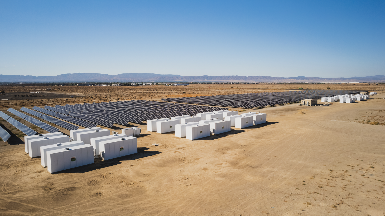 Old EV batteries stacked in trailers hold the solar energy the panels gather during the day.