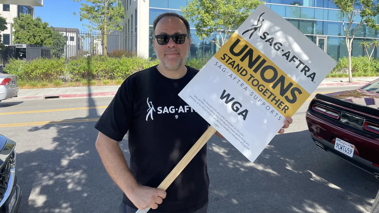 An actor on strike holds a sign that says, “Unions stand together. SAG-AFTRA supports WGA,” July 13, 2023.