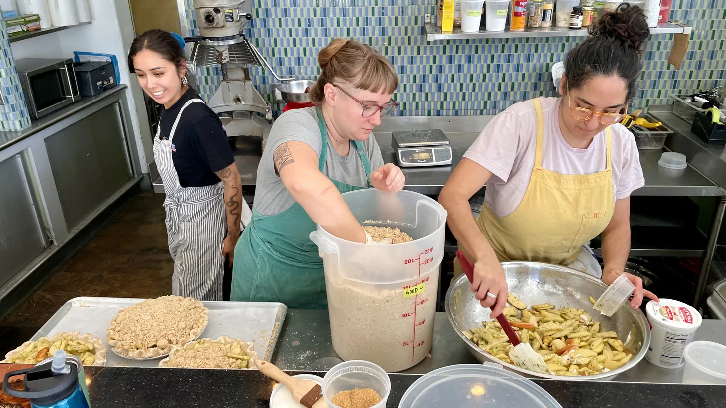 Professional bakers Catalina Flores (left) looks on as Kelly Delany (middle) tops apple pies with crumble, and Sasha Piligian (right) mixes filling. Pie makers across Los Angeles have been working around the clock to bake enough dessert for Thanksgiving dinner.