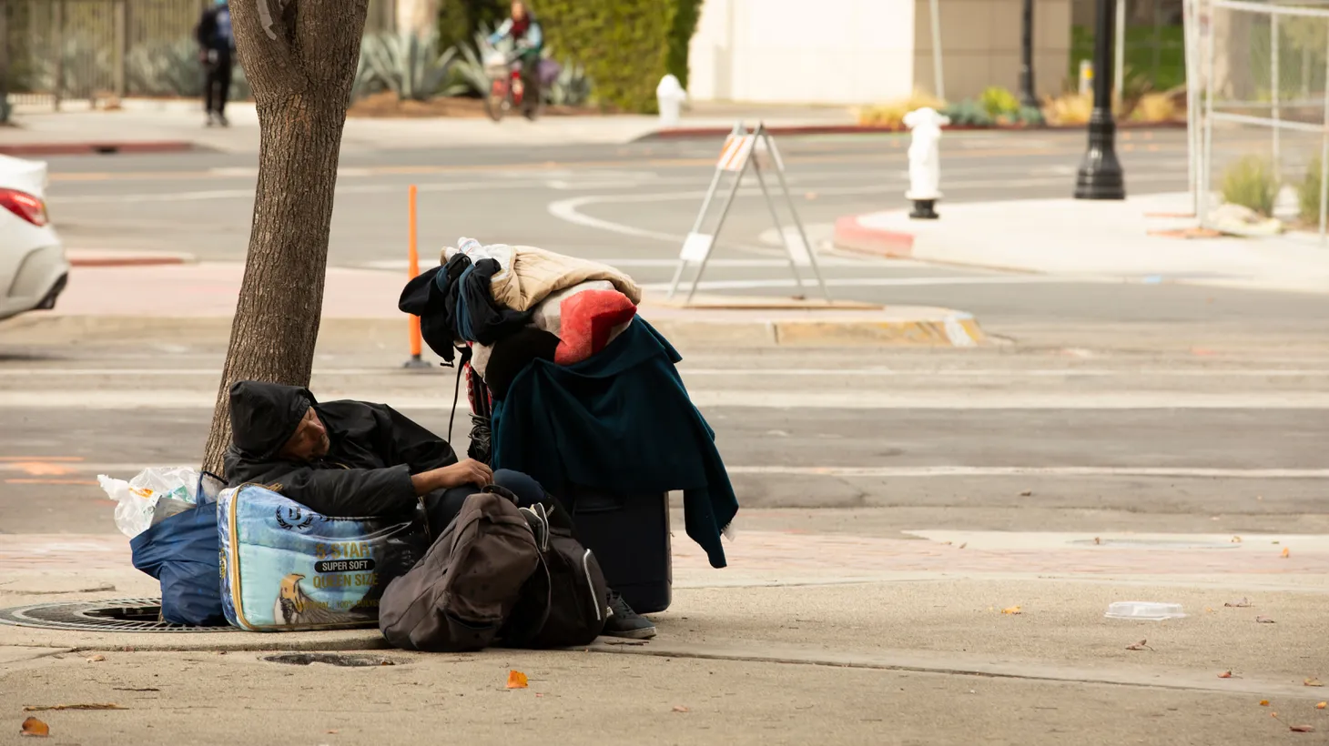 An unhoused person sits on the sidewalk in Santa Ana, December 2020.