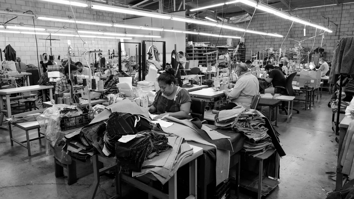 Under fluorescent light, men and women stay focused during the work day at 9B Apparel in Huntington Park, CA, August 26, 2022.