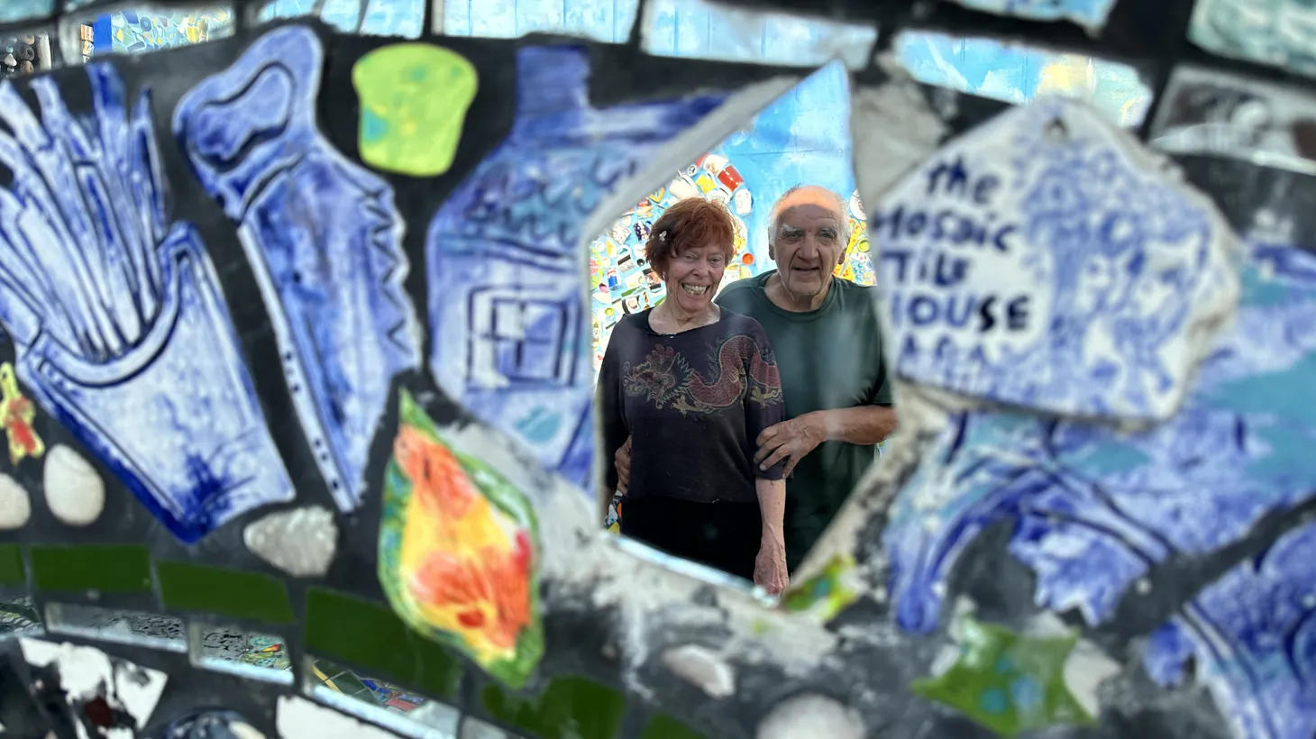 Cheri Pann and Gonzalo Duran stand reflected in the mosaic mirrors plastering the garden wall of the home the pair have decorated inside and out with mosaic tile art and paintings.