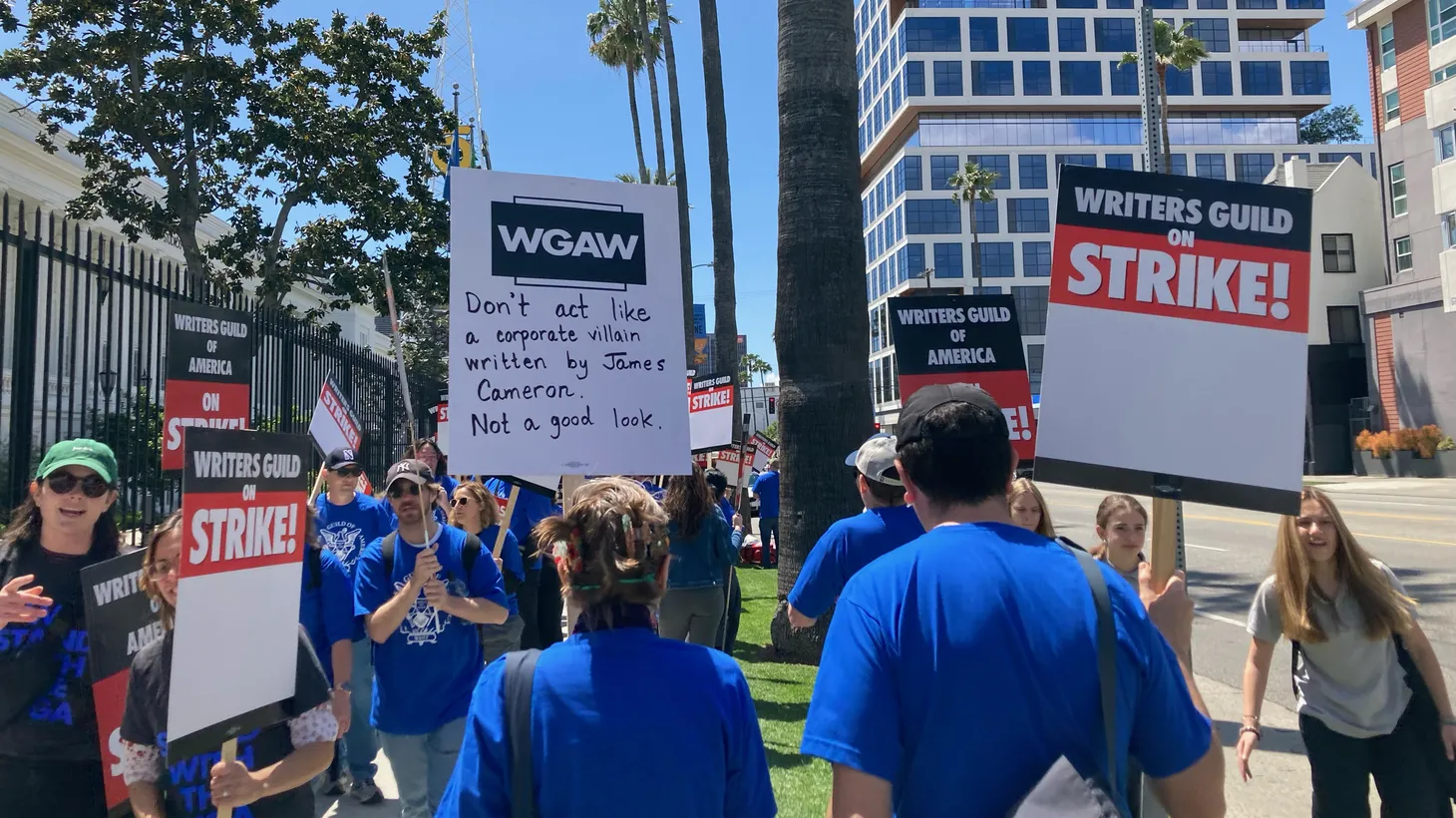 Hollywood writers carry signs during a strike. “Don’t act like a corporate villain written by James Cameron. Not a good look,” says one sign. May 2, 2023 in Los Angeles.