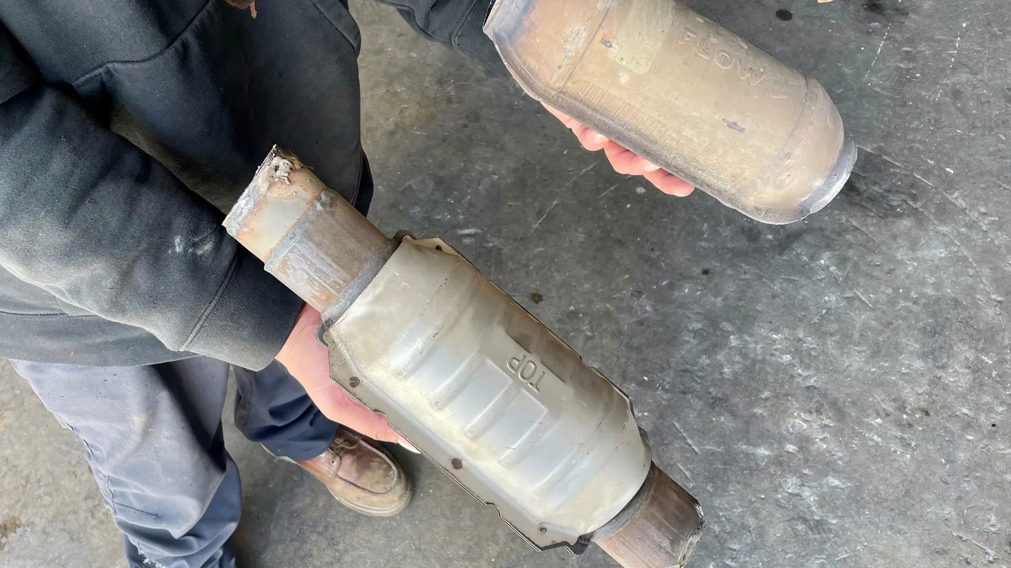 Van Nuys mechanic Edward Luna holds two used catalytic converters, which thieves are stealing from cars in record numbers across Los Angeles.
