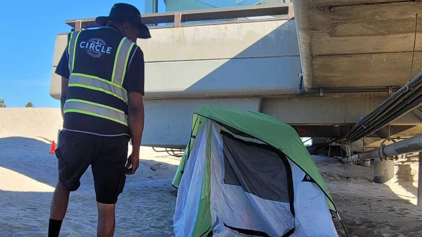 An LA CIRCLE team outreach worker approaches a tent on an LA beach.