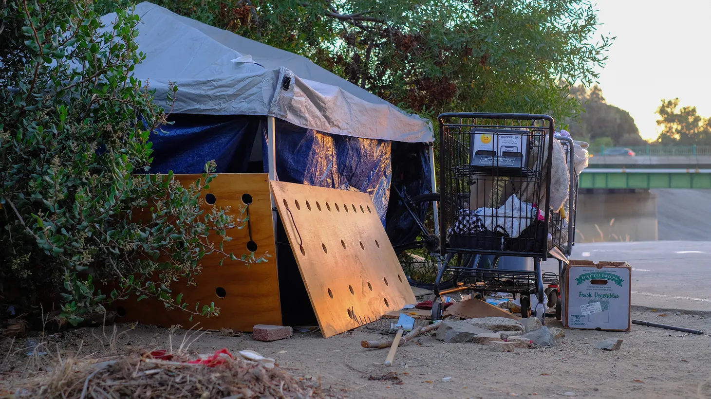 A homeless camp sits along the Ballona Creek trail in Culver City near sunset.