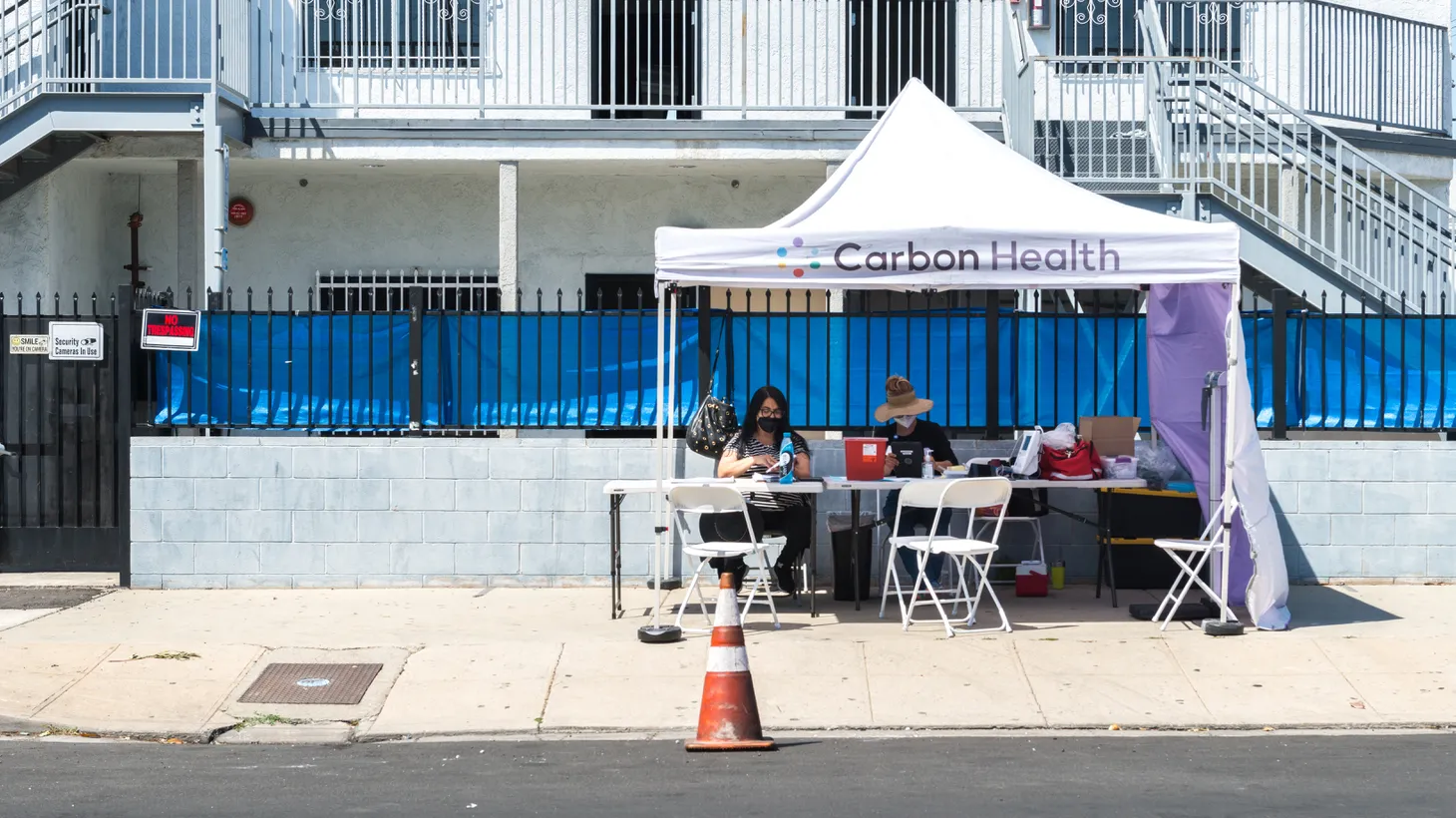 Nurse Gita Ahadi and community organizer Mari Mercado wait for people to show up at Carbon Health’s pop-up vaccination clinic in South Central Los Angeles, across the street from South LA Cafe. Mercado is offering a $50 gift card to encourage people to get vaccinated.
