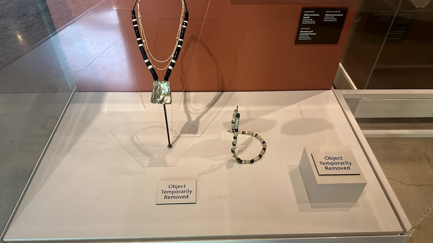 The Natural History Museum of Los Angeles County puts “object temporarily removed” signs in a display case of Native American jewelry.