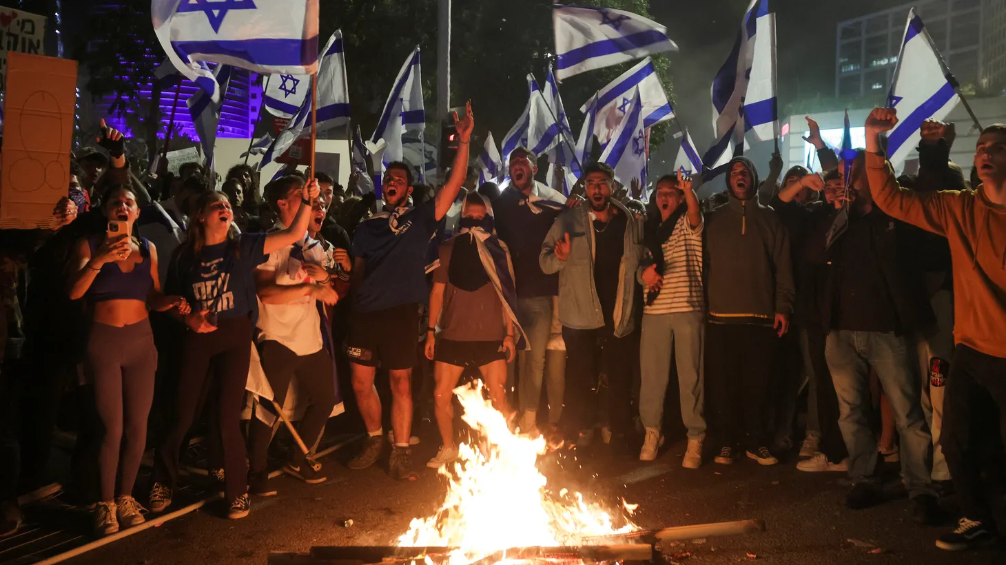 Israeli protesters chant in front of a burning fire at a demonstration against Israeli Prime Minister Benjamin Netanyahu and his nationalist coalition government's plan for judicial overhaul, in Tel Aviv, Israel, March 27, 2023.