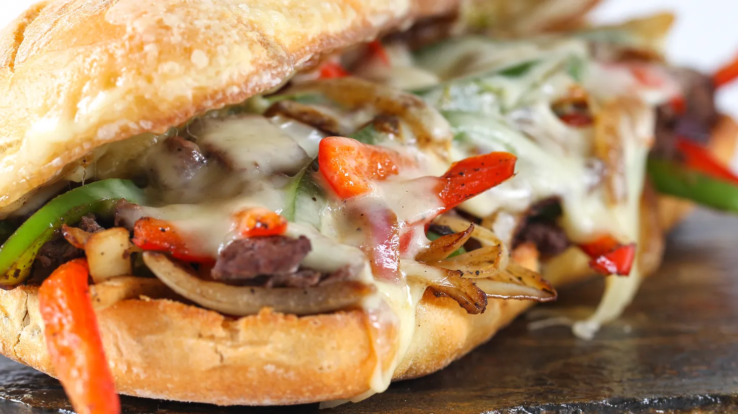 A traditional Philly Cheesesteak sandwich is topped with onions, mushrooms and provolone.