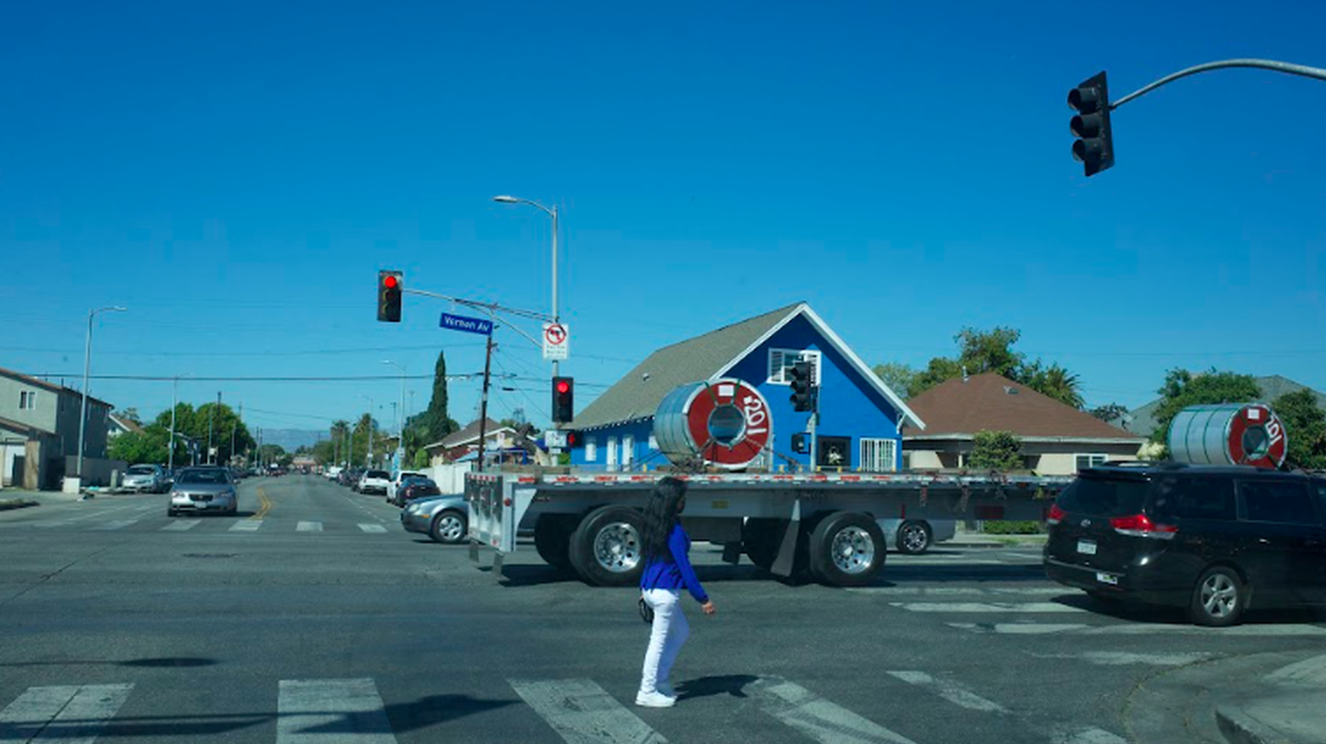 A person walks through a traffic intersection at Vernon Ave. and San Pedro St. in South LA.