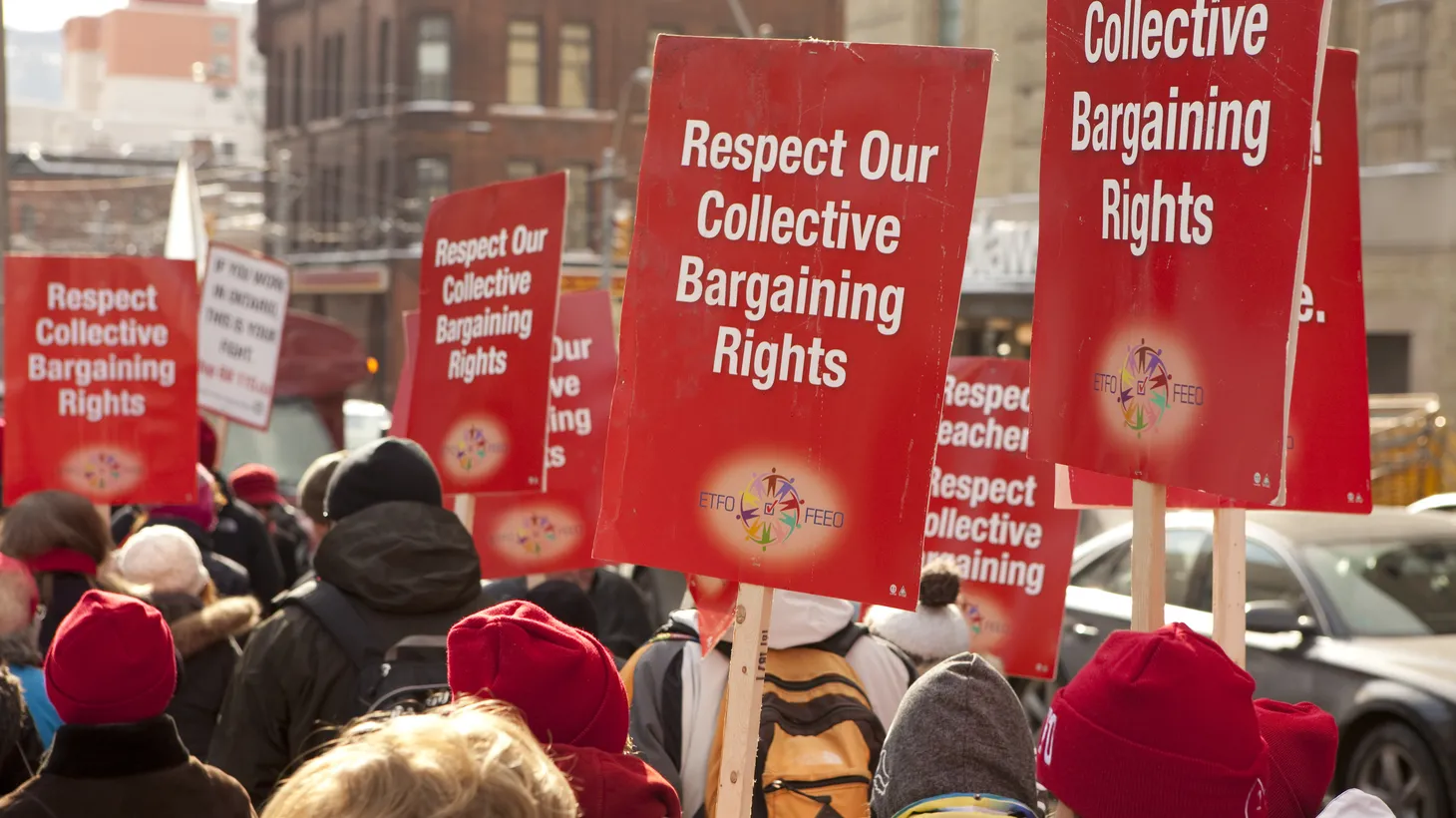 Activists hold signs that say “respect our collective bargaining rights.”