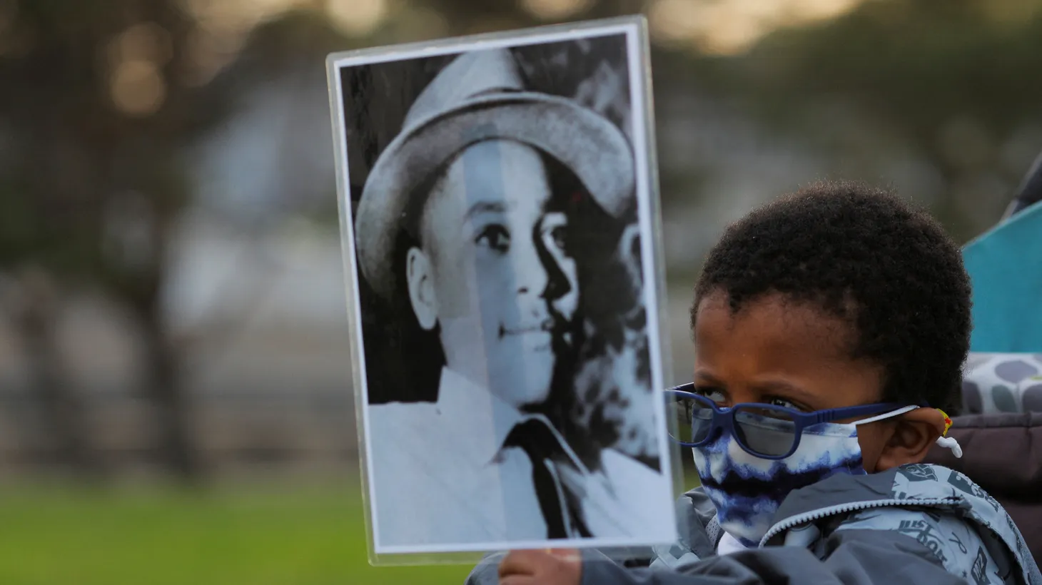 A four-year-old holds a photograph of Emmett Till, a 14-year-old Black boy who was lynched in 1955, at a vigil on the one-year anniversary of George Floyd’s murder on May 25, 2021.