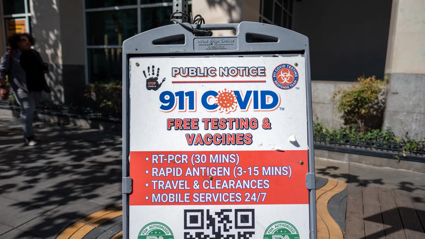 A public notice sign advertises “911 COVID free testing and vaccines” in Santa Monica, CA.