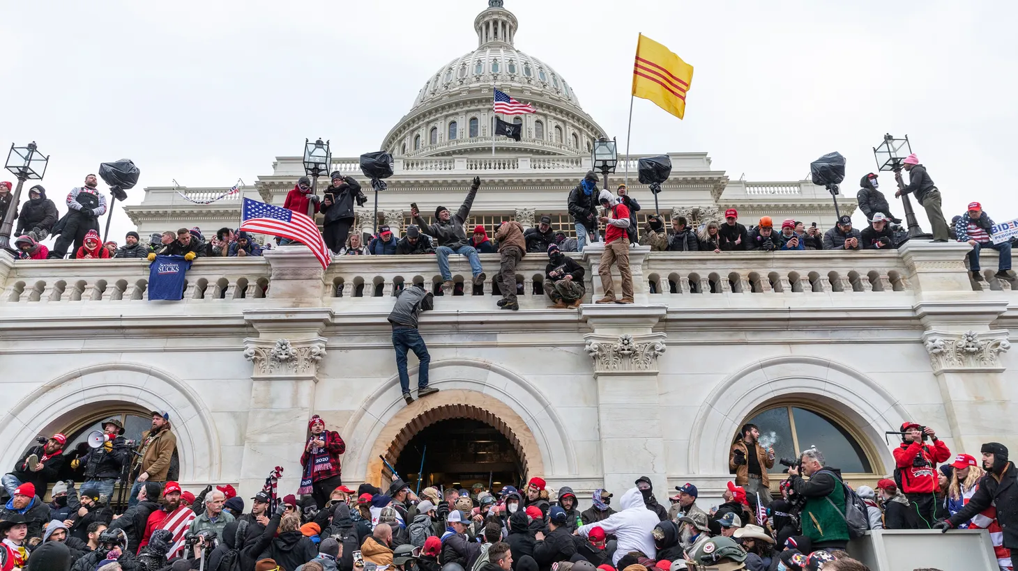 Rioters scale a wall of the U.S. Capitol on January 6, 2021.