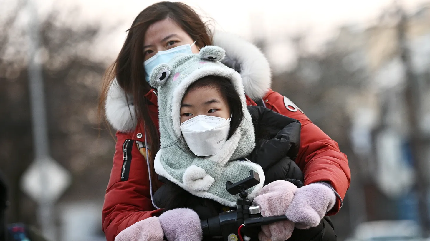 A child wears a mask while being accompanied to school on a scooter in Queens, NY, February 8, 2022. New Jersey Gov. Phil Murphy said he will rescind the mask mandate for students and teachers on March 7. Pressure mounts for NY Gov. Kathy Hochul to do the same, as daily positivity rates in New York City schools fall below 1%.