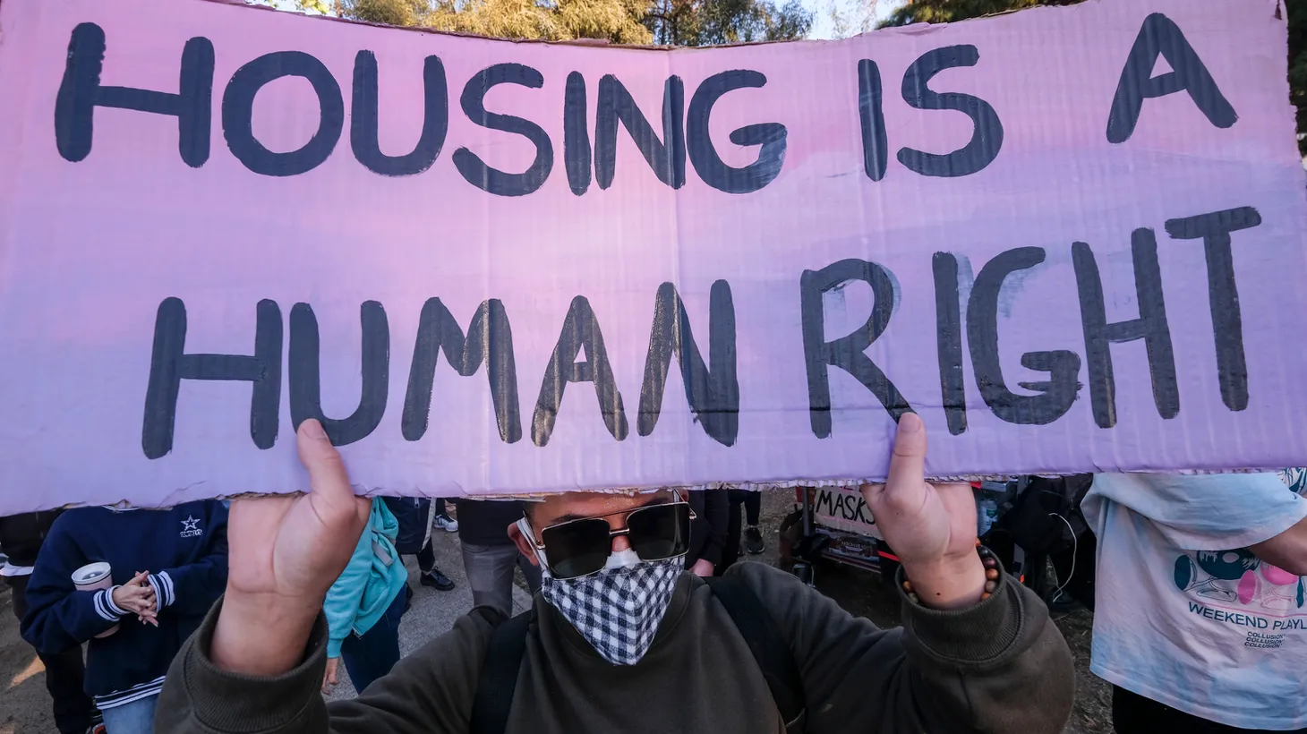 An activist holds a sign that says “housing is a human right,” at Echo Park Lake, March 24, 2021.