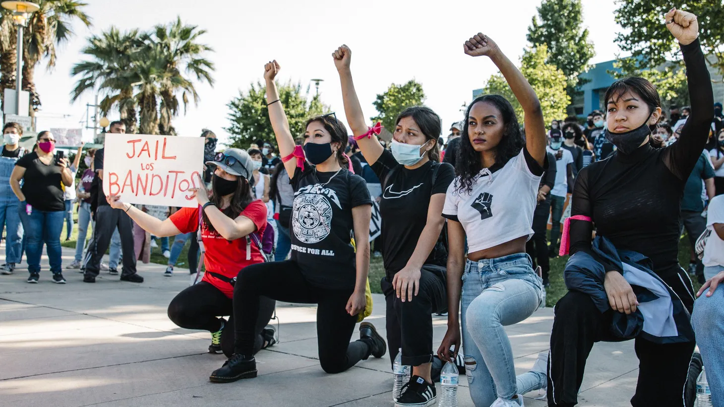 Young activists kneel and hold their fists in the air while facing the East LA Sheriff's station in Belvedere Park. They were part of a rally in solidarity with Black Lives Matter, on June 7, 2020.