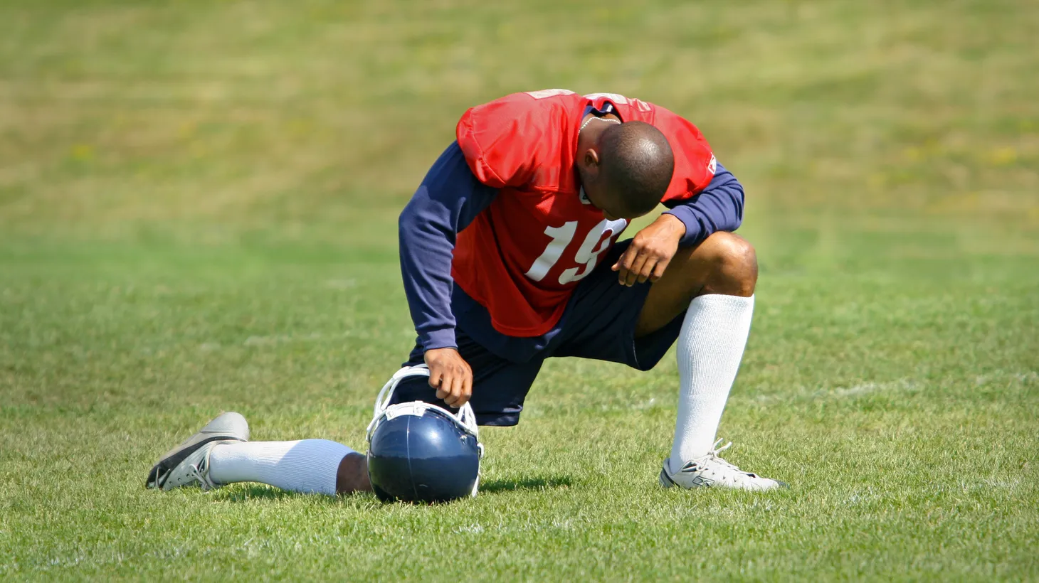 A football player prays on one knee. Football coach Joseph Kennedy in Washington state says his contract was not renewed because he publicly led prayers after a game.