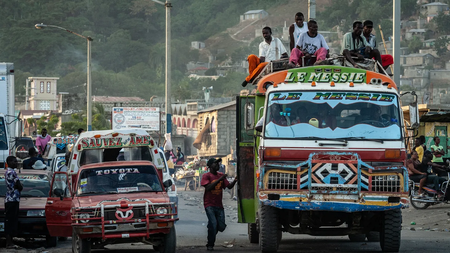 Passengers ride on the roof of a bus in Cap-Haïtien, Haiti, a country still struggling with poverty.