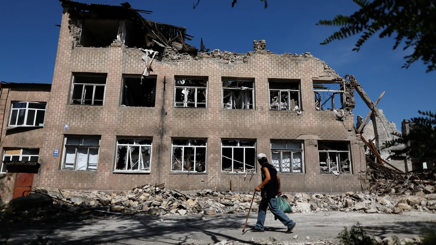 A man walks near a destroyed school, as Russia's attack on Ukraine continues, in Toretsk, Donetsk region, Ukraine, August 22, 2022.