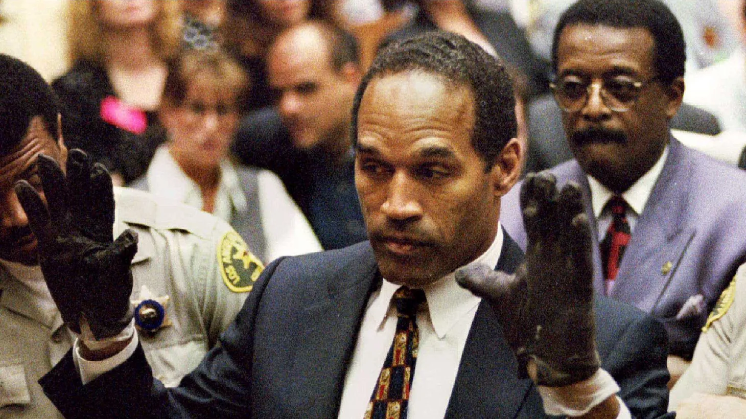 O.J. Simpson, wearing the blood-stained gloves found by Los Angeles Police and entered into evidence in Simpson's murder trial, displays his hands to the jury at the request of prosecutor Christopher Darden as his attorney Johnnie Cochran, Jr. (R.) looks on, June 15, 1995.
