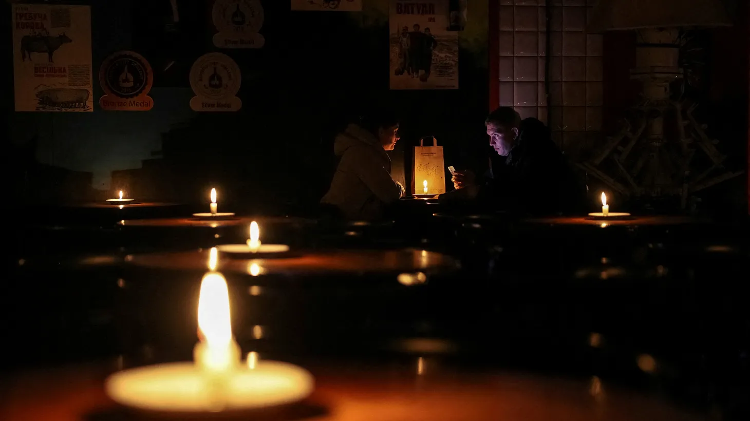 People sit in a pub lit with candles during a power outage after critical civil infrastructure was hit by Russian missile attacks, as Russia's invasion of Ukraine continues, in Lviv, Ukraine, November 24, 2022.
