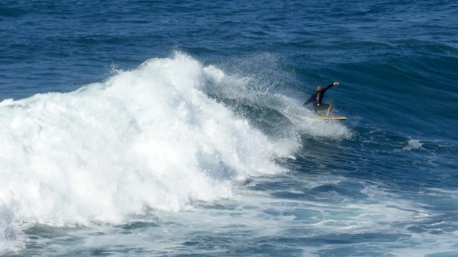 A person surfs a wave in Manhattan Beach, California.