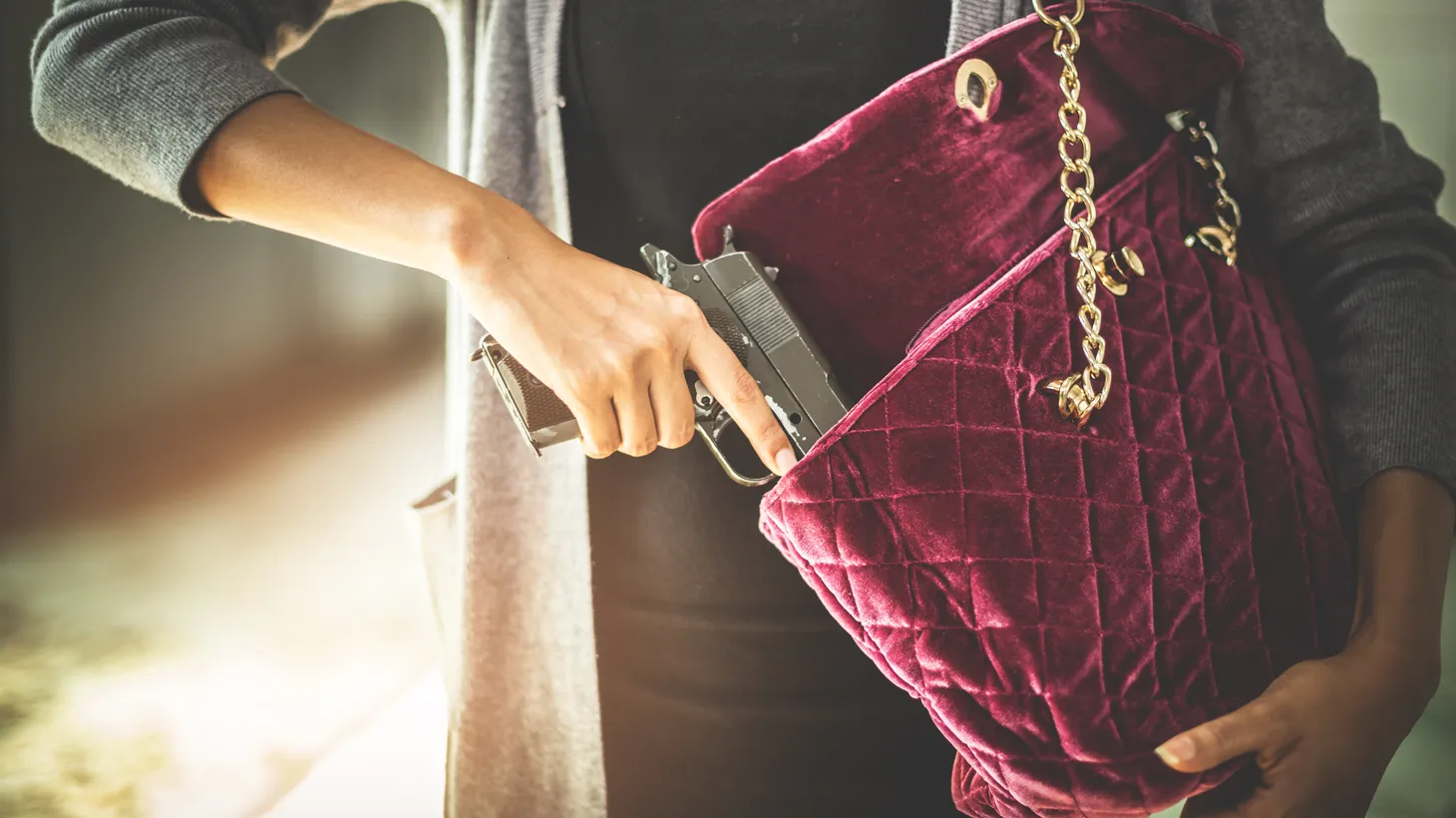 A woman outdoors pulls a gun from her purse. “The conservative Supreme Court has given us a new, more stringent level of review to use when looking at gun control measures,” says Loyola Law School professor Jessica Levinson.