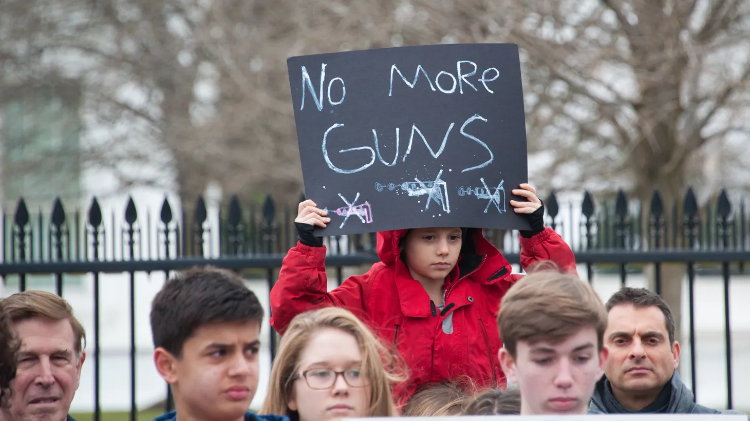 An activist in front of the White House holds a sign that says, “No more guns,” February 19, 2018 in Washington, D.C.