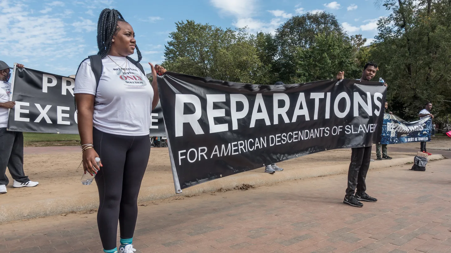 Activists hold a sign pushing for reparations for American descendants of enslaved people.