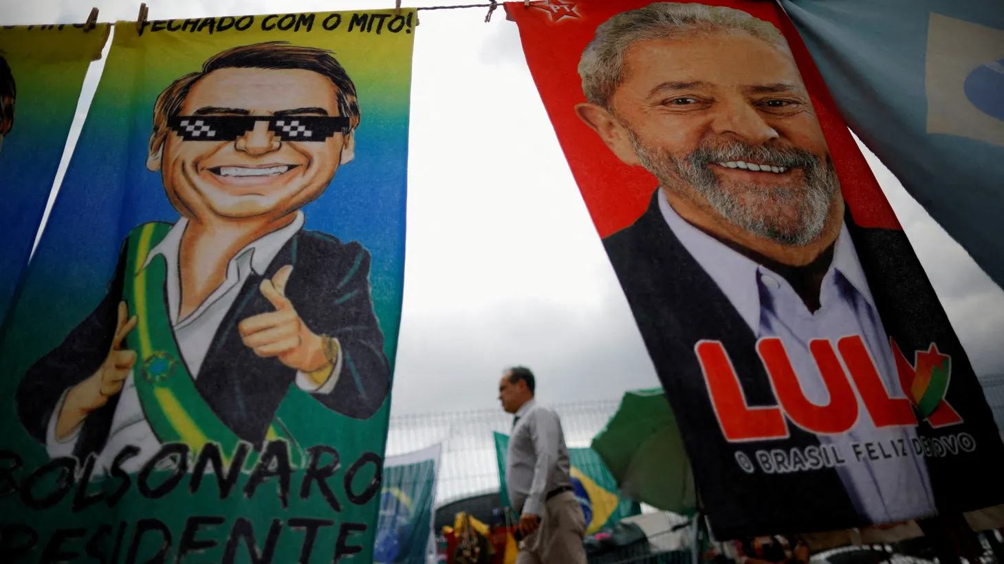 A man walks past presidential campaign materials depicting President Jair Bolsonaro and former President Luiz Inacio Lula da Silva in Brazil, September 23, 2022.